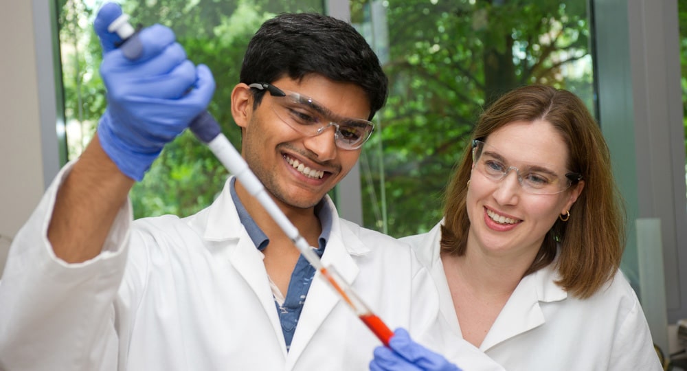 Graduate research assistant holding a vial while professor observes