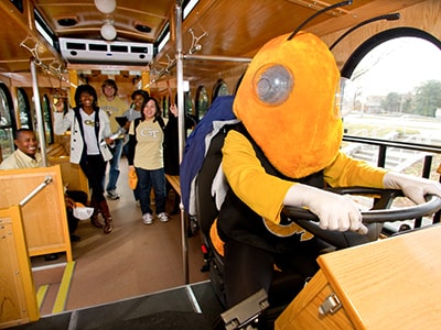 Yellow Jackets mascot, Buzz, driving a Tech trolley